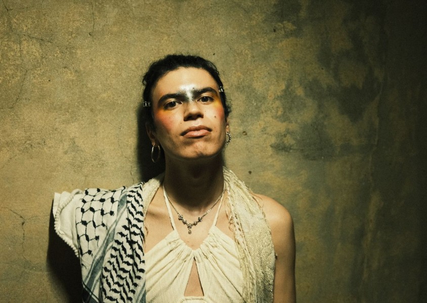 Jacob Alon wearing a white dress and keffiyahx